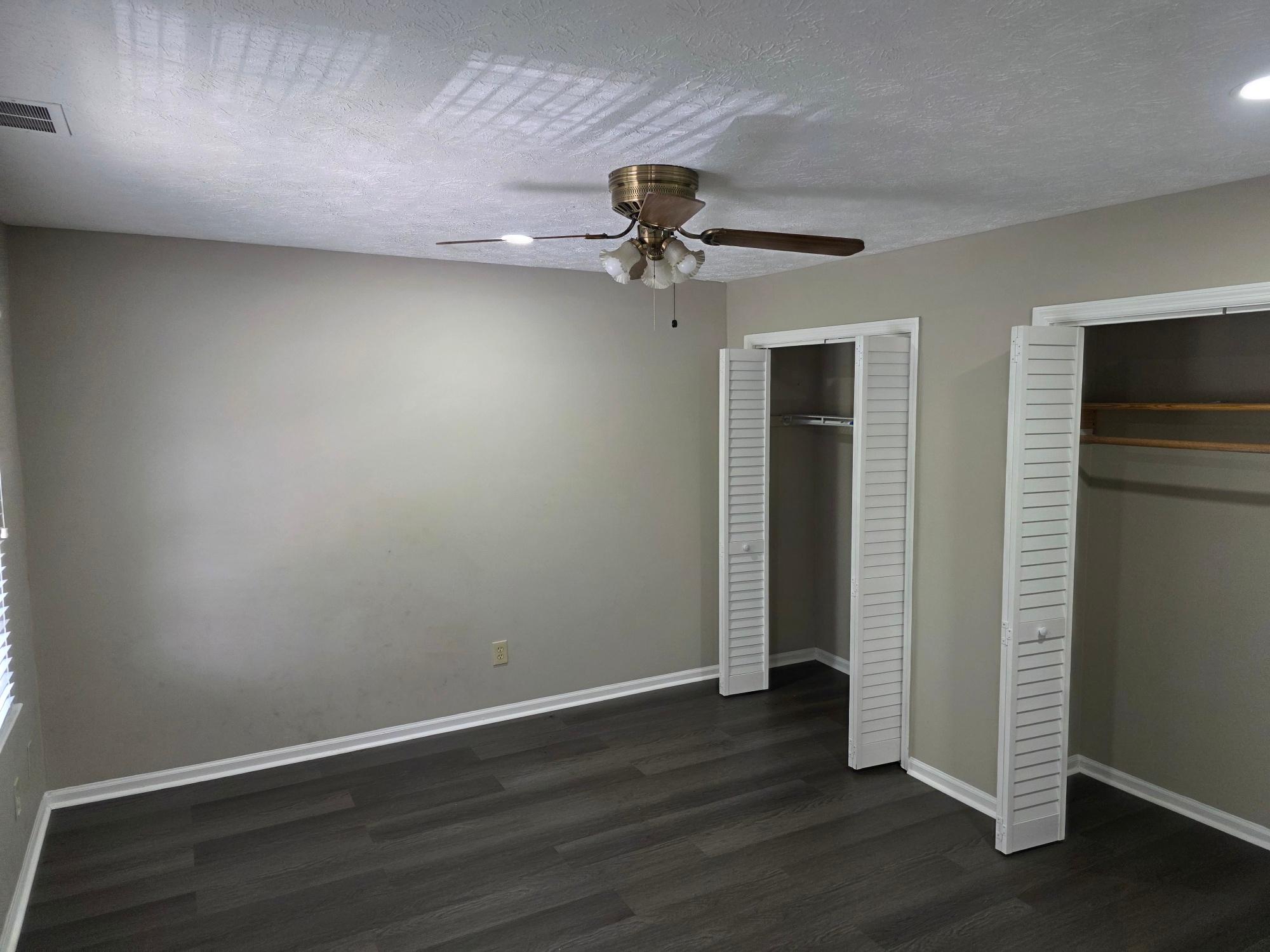 Bedroom with ceiling fan and twin louvered closets